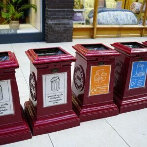 A row of red clocks sitting on top of a sidewalk
