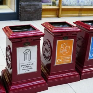 A row of red clocks sitting on top of a sidewalk