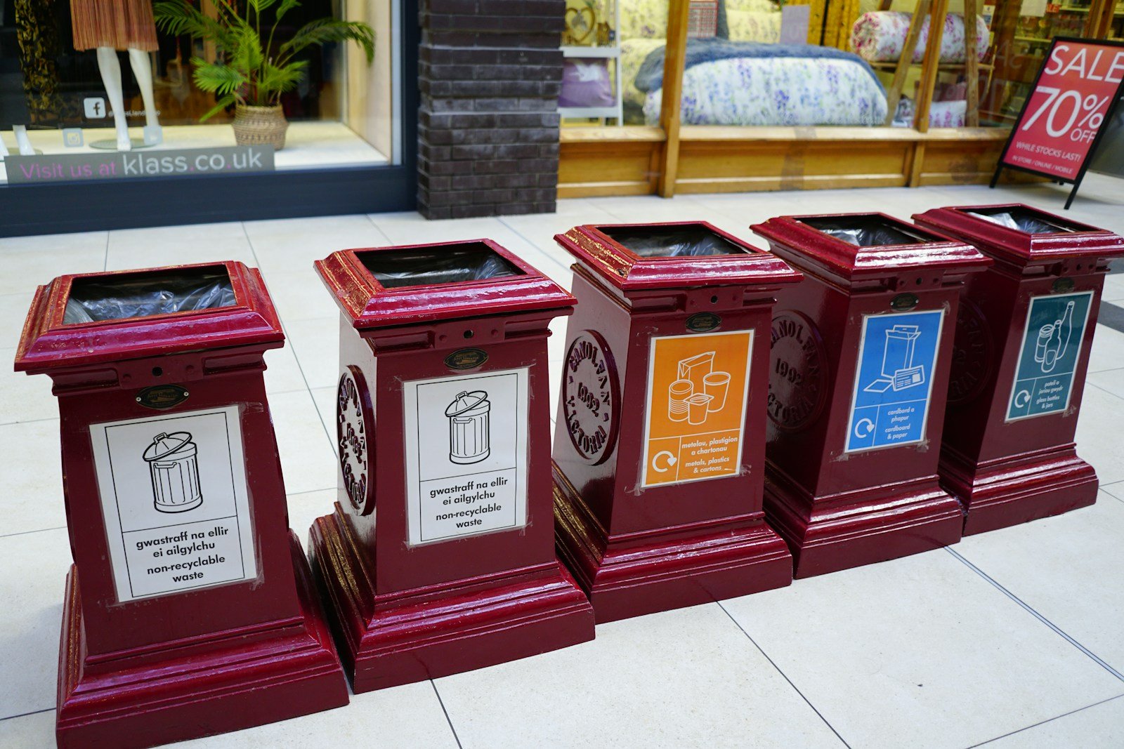 A row of red clocks sitting on top of a sidewalk