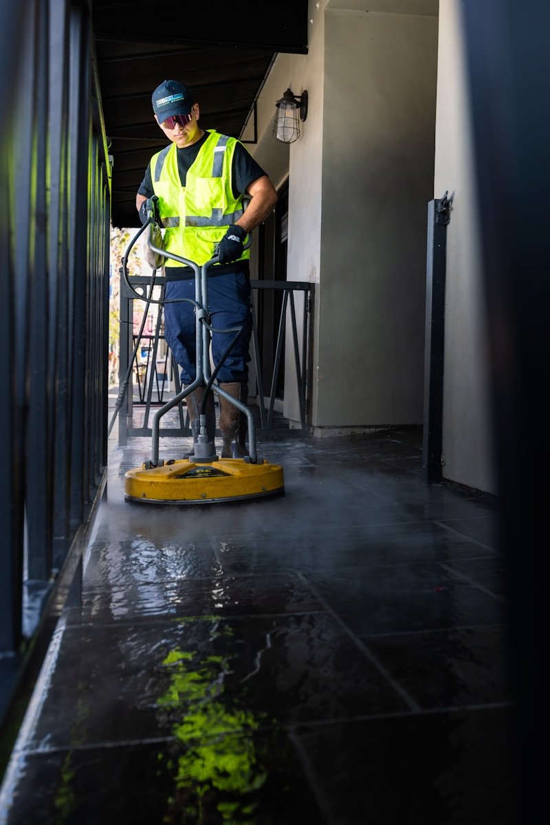 a man in a yellow vest is cleaning the floor